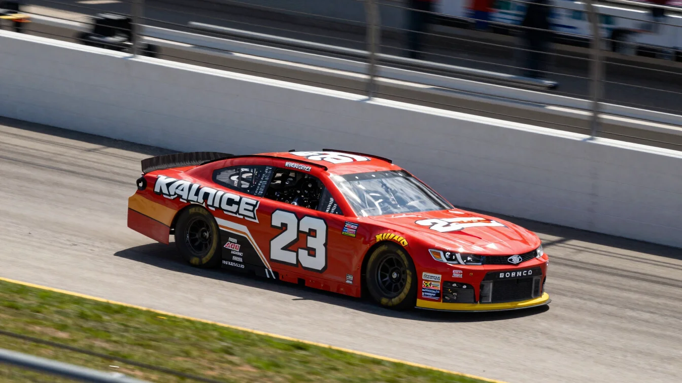 NASCAR stock car on a banked oval track, high-contrast sunlight,